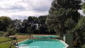 Una piscina elevada rectangular con una escalera en el lado izquierdo, rodeada por un solárium de hormigón.