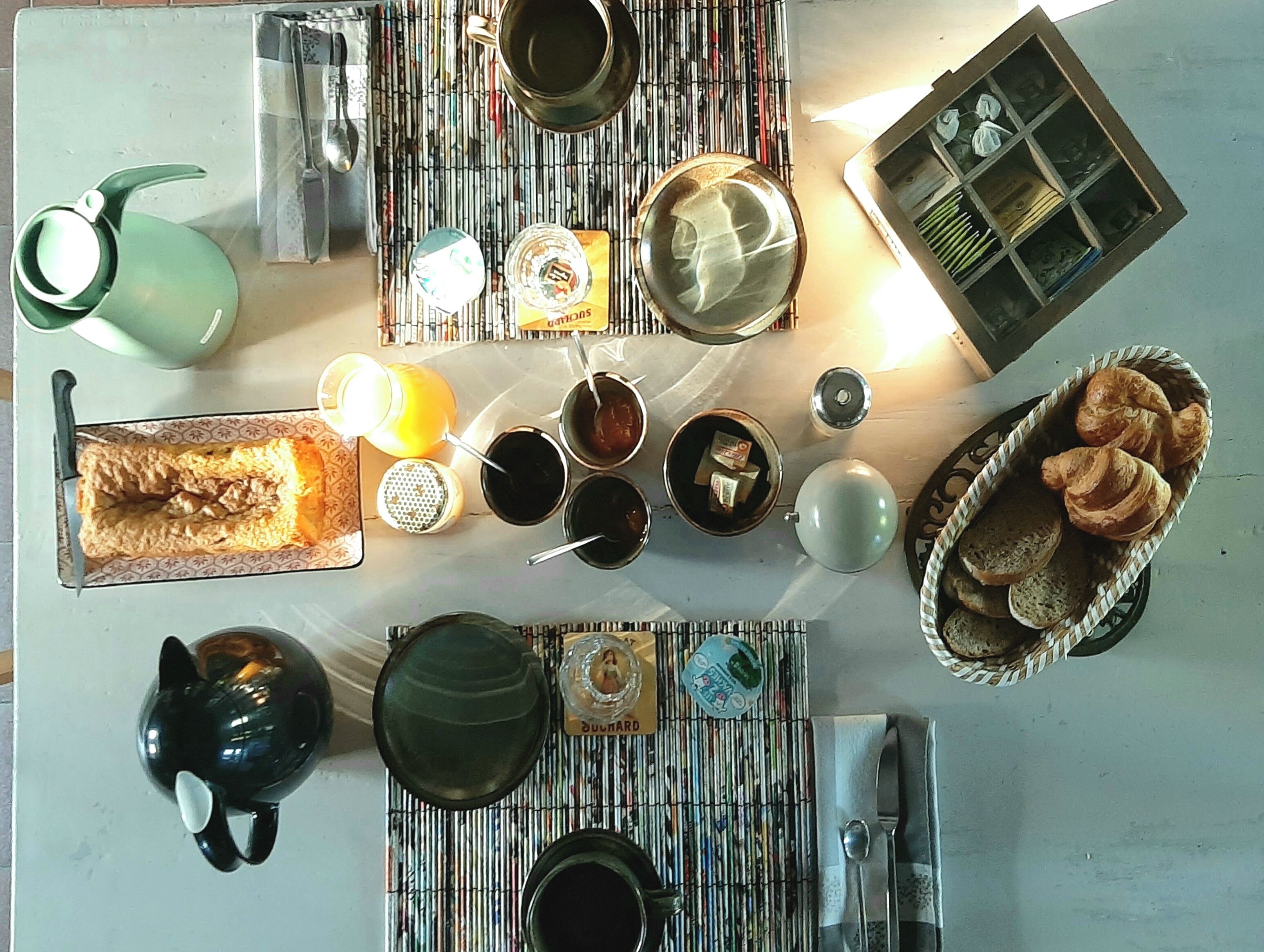 A dining table with various dishes, utensils, and a basket of bread.