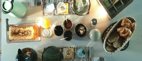 A dining table with various dishes, utensils, and a basket of bread.