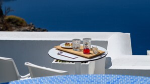 Taula amb un plat de menjar i begudes, amb vista a un paisatge maritim idíl·lic d'unes illes.