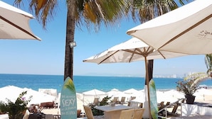 A beachside patio with white umbrellas, lounge chairs, and a table. - Le Petit Bonheur • Quiet • Rooftop • 3 min to Beach (5 de Diciembre)