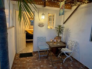 A cozy corner with a table, two chairs, a potted plant, and a wall sign.