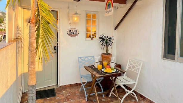 A patio with a table, chairs, a potted plant, and a sign with 'LGBT love peace' and 'LE P'TIT BONHEUR' on the wall. - Le Petit Bonheur • Quiet • Rooftop • 3 min to Beach (5 de Diciembre)