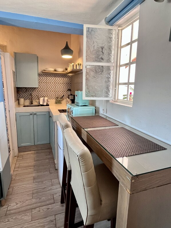 A kitchen with a built-in bench, a window, and a herringbone-patterned backsplash.