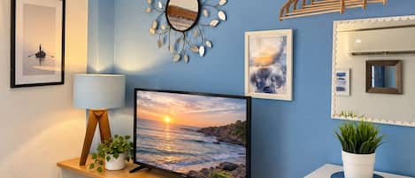 Una stanza con una televisione su un supporto in legno, uno specchio a parete e un appendiabiti.