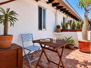 A patio with a wooden table and blue chair, surrounded by potted plants and a tiled floor. - Le Petit Bonheur • Quiet • Rooftop • 3 min to Beach (5 de Diciembre)