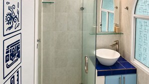 Une salle de bain avec une douche à parois de verre, un lavabo blanc et un miroir au-dessus.