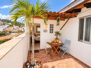 A small patio with a table, chairs, a potted plant, and a view of the surrounding neighborhood. - Le Petit Bonheur • Quiet • Rooftop • 3 min to Beach (5 de Diciembre)