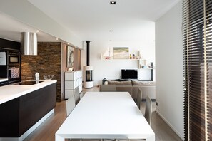 Et moderne køkken med en central ø, indbygget ovn og bagplade i sten.