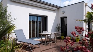 Una casa moderna con un patio, un tavolo da pranzo con sedie e piante in vaso.