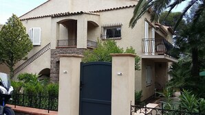Un edificio residencial con entrada protegida por un portón, varios balcones y una escalera que lleva a un piso superior.