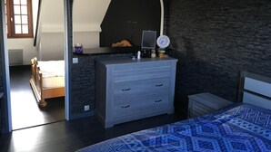Ein Schlafzimmer mit einem Bett, einem Schminktisch und einem Spiegel. Auf dem Schminktisch steht eine Uhr.