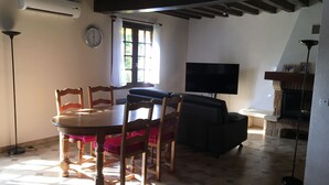 Ein Essbereich mit einem runden Tisch, Stühlen, einem Fernseher und einem Kamin.