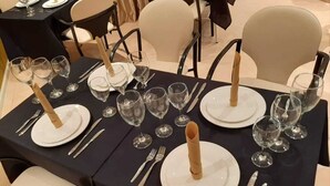 Ett matbord dukat med vita tallrikar, silverbestick och vinglas, och en vackert vikt servett som mittpunkt.