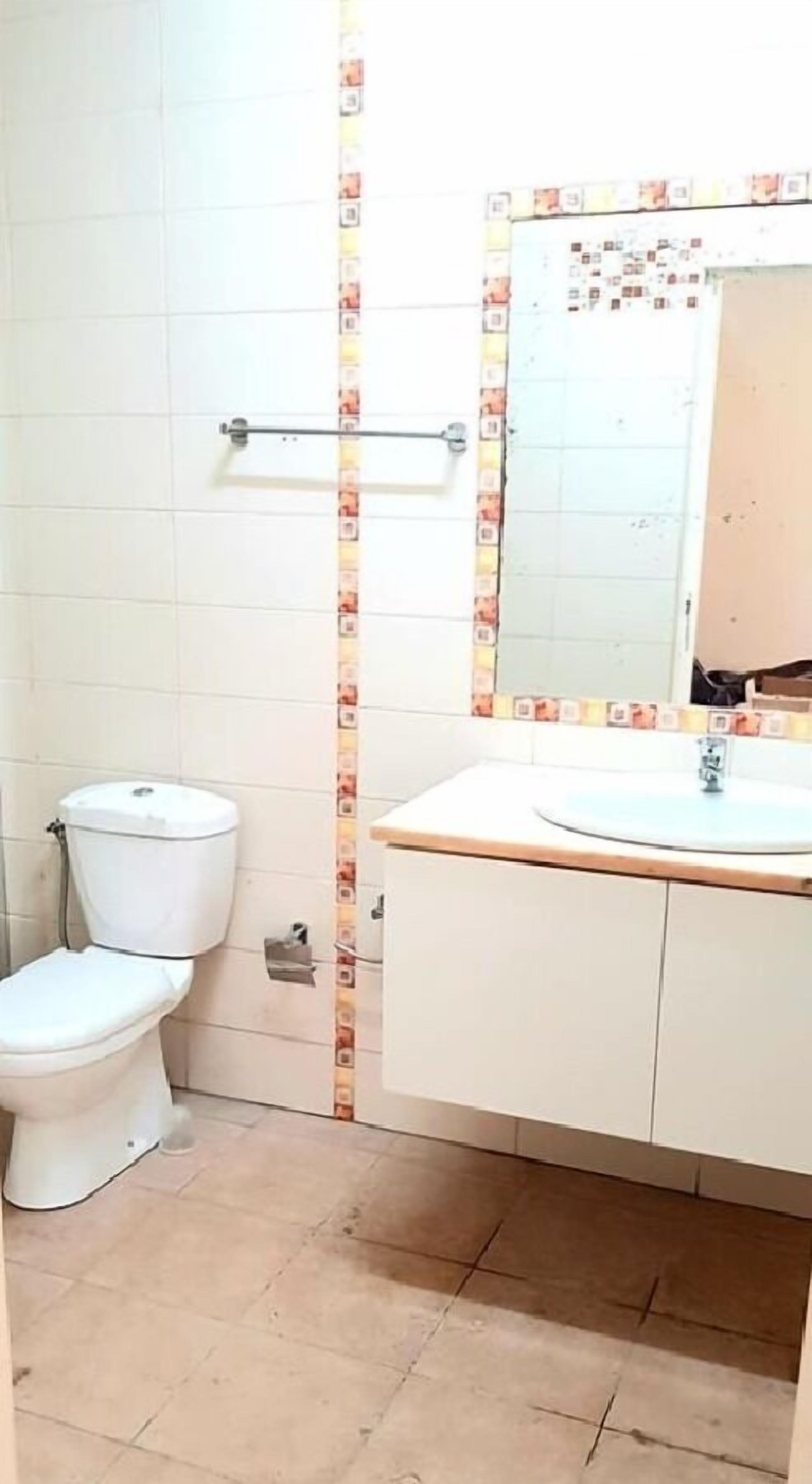 A bathroom with a toilet, sink, and mirror.