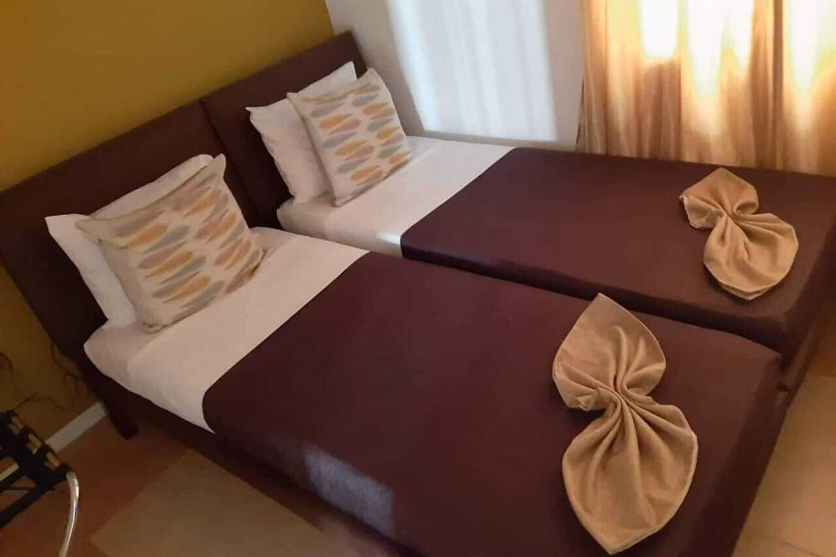 A hotel room with two beds, each with a brown headboard and a white bedspread.