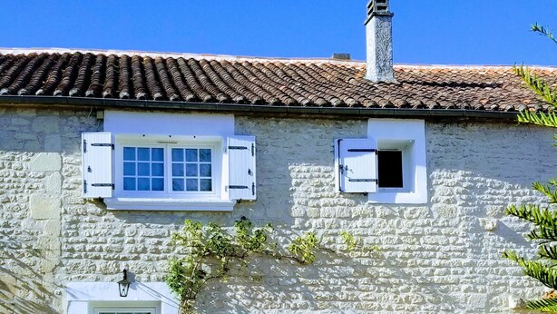 Un edificio de piedra con techo de tejas, una ventana pequeña y una puerta.