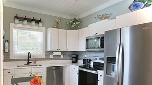 A modern kitchen with stainless steel appliances, white cabinetry, and decorative wall art.