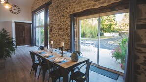 A dining area with a stone wall, large windows, and a view of the outdoors. - Exceptional house with heated pool - 8 people (Saint-Georges-de-Pointindoux)