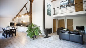 A spacious living area with a dining table, sofas, a fireplace, and a kitchen in the background. - Exceptional house with heated pool - 8 people (Saint-Georges-de-Pointindoux)