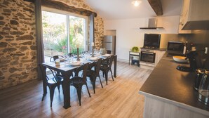 A kitchen with a stone wall, wooden floor, and modern appliances. - Exceptional house with heated pool - 8 people (Saint-Georges-de-Pointindoux)
