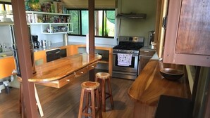 Una cocina compacta con encimera de madera, dos taburetes, horno integrado y ventana que proporciona luz natural.