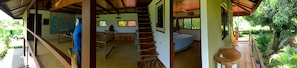 A multi-level room with a staircase, a bed, a desk, and a window with a view of greenery.