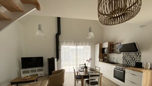 Um apartamento moderno com área de jantar, cozinha, sala de estar e televisão.