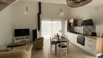 A modern apartment with a dining area, kitchen, living room, and a TV.