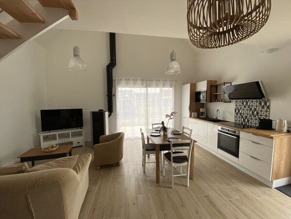 A modern apartment with a dining area, kitchen, living room, and a TV.
