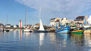Um porto com vários barcos atracados, um farol e edifícios ao fundo.