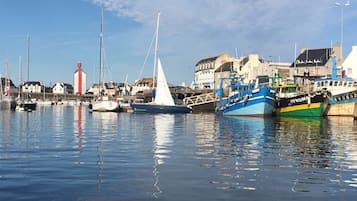A harbor with various boats docked, a lighthouse, and buildings in the background.