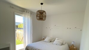 Quarto com cama, luminária pendente, mesa de cabeceira e vista para o exterior.