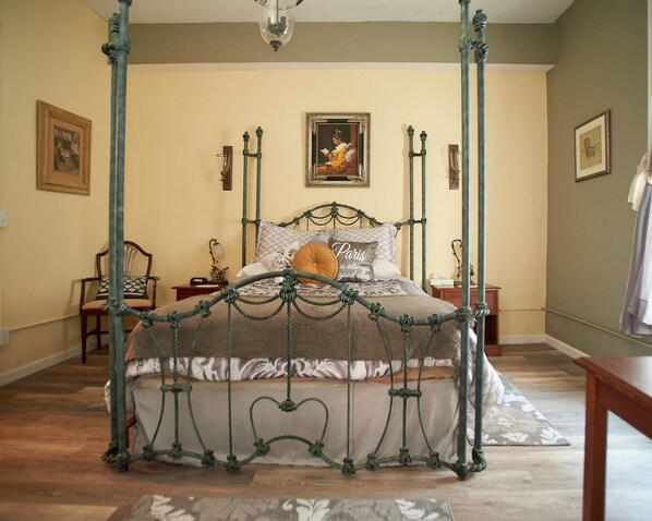 Classic four-poster bed with patterned bedding and a decorative pillow, set against a neutral backdrop.