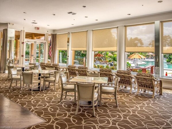 A hotel lobby with a pool view, featuring a patterned carpet, wicker furniture, and large windows. - Resort-style condo - close to great beaches and downtown Naples. (Naples)