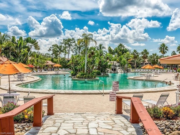 A resort pool area with multiple pools, palm trees, and lounge chairs.