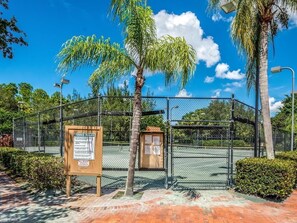 A tennis court with a fence, palm trees, and a signboard with rules. - Resort-style condo - close to great beaches and downtown Naples. (Naples)