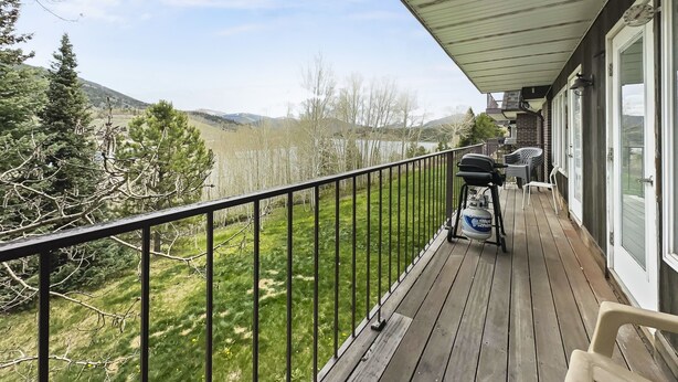 Eine Holzterrasse mit Geländer, Grill und Gartenmöbeln.