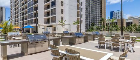 An outdoor patio with a grill, seating, and a view of tall buildings.