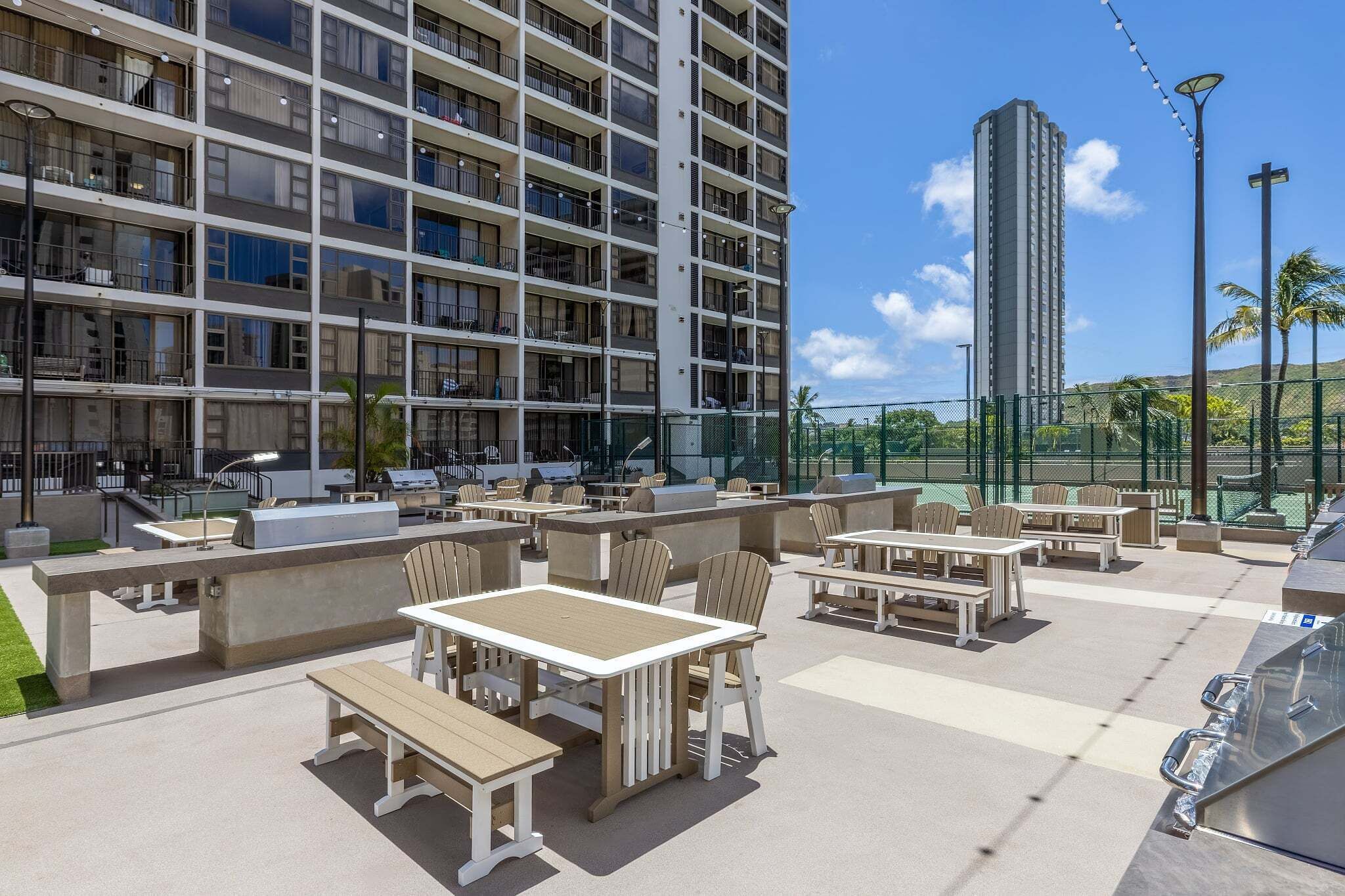 Una terrazza sul tetto con posti a sedere all'aperto, un barbecue e vista su un edificio alto.