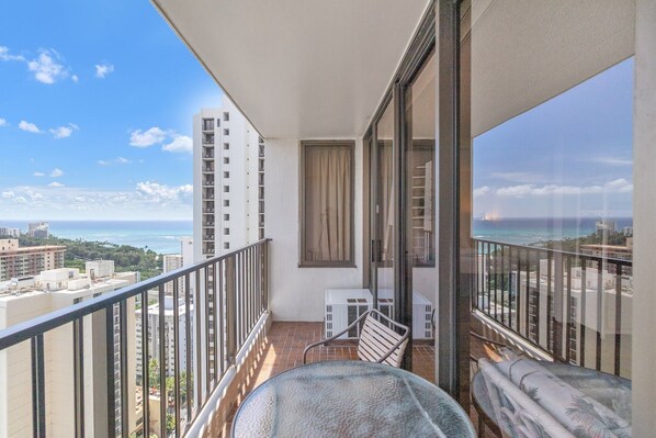 Ein Balkon mit Blick auf das Meer und die Stadt, ein Stuhl und ein kleiner Tisch.