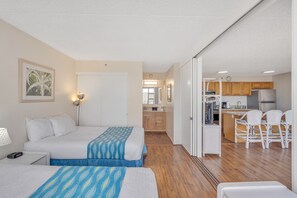 Ein Hotelzimmer mit zwei Betten, einer Küchenzeile und einem Essbereich mit Stühlen.