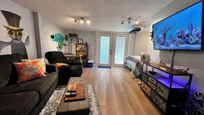 Un salon avec un canapé, une table basse, un téléviseur et une grande fenêtre.