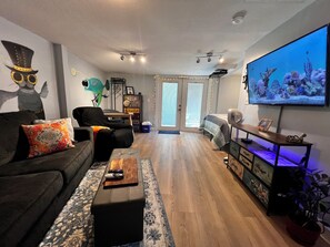 Een woonkamer met een bank, een salontafel, een televisie en een groot raam.