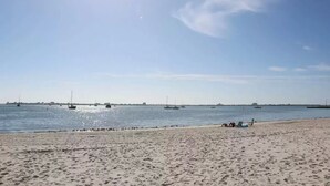 Une plage avec des bateaux sur l’eau et des gens sur le sable.