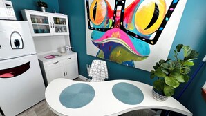 Une cuisine avec un réfrigérateur blanc, un meuble de rangement blanc, un mur bleu et un grand tableau représentant un papillon.