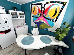 Une cuisine avec un réfrigérateur blanc, un meuble de rangement blanc, un mur bleu et un grand tableau représentant un papillon.