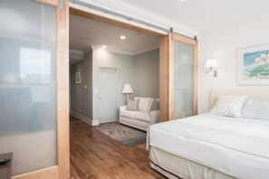 Une chambre à coucher comprenant un lit, une table de chevet, une lampe et une porte coulissante donnant sur une salle de bain.