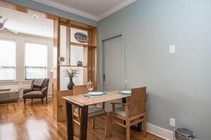 Un coin repas avec une table et des chaises en bois, un vase et une étagère murale agrémentée d’objets décoratifs.