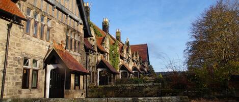 A historic stone building with multiple chimneys and a steeply pitched roof.